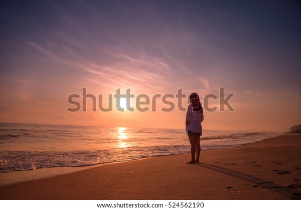 砂浜の夕日に立つ孤独な女性 の写真素材 今すぐ編集