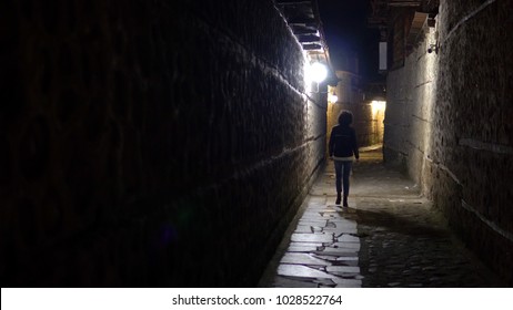 Lonely woman walk in old stone pavement alley at night in the back street