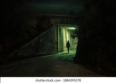 Lonely woman walking in a dramatic mystic dark alley at night. Danger and scary concept. - Powered by Shutterstock