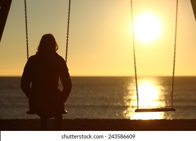 Lonely woman watching sunset alone in winter on the beach at sunset
