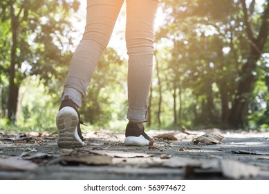 Lonely Woman Wearing Jeans And Black Sneakers Walking Along The Path In The Park.