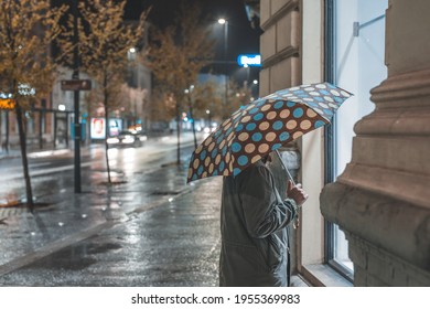 Lonely Woman Window Shopping Alone At Night During Rain. Rainy Stroll Through The City.