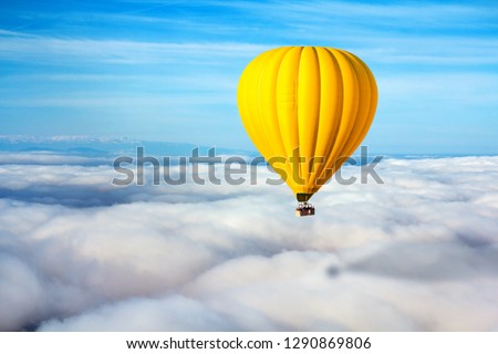 A lonely yellow hot air balloon floats above the clouds. Concept leader, success, loneliness, victory