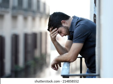 Lonely Young Man Outside At House Balcony Looking Depressed, Destroyed, Sad And Suffering Emotional Crisis And Grief Thinking Of Taking A Difficult And Important Life Decision On An Urban Background