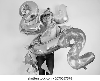lonely young woman celebrating new year 2022 at home quarantine. the end of year. girl wearing partyglasses  and posing with big number balloons near white wall. silvester 2022. greeting card. 22.