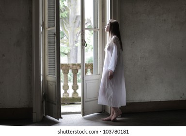 Lonely Young Woman Looking Out Of A Window