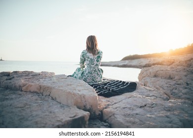 Lonely young woman sitting on beach