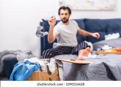 Loner Throwing Dirty Sock Into Basket With Laundry In Bedroom