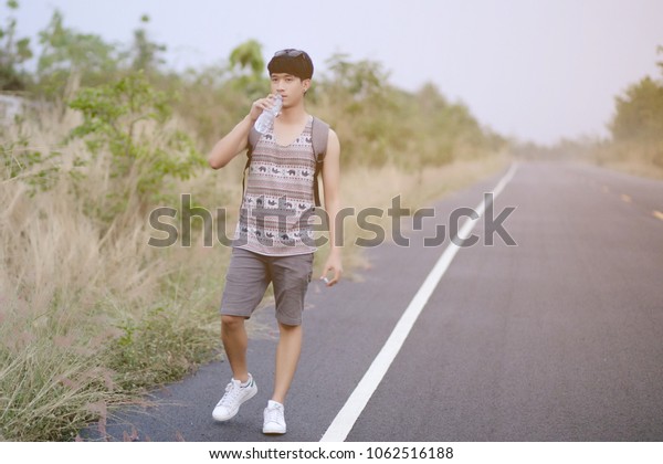 loner walking down an empty road and hot.\
Road hitch-hiking.