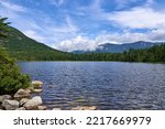Lonesome Lake is a pristine glacial lake in Franconia Notch State Park in the White Mountains of NH, in Franconia, NH on a summer day with blue sky and dramatic clouds.