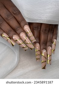 Long acrylic coffin nails set with abstract design in gold color, gold chrome design on long nails - Shutterstock ID 2345891187
