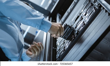 Long Angle Shot In Fully Working Data Center IT Engineer Installs Hard Drive Into Server Rack. Detailed And Technically Accurate Footage.