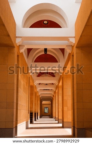 Long arcade corridor with ocre stone pillars and white arches inside Sheikh Mohammed Bin Ibrahim Mosque in Riyadh, Saudi Arabia