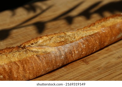 Long Baguette On Wooden Chopping Board With Shadows