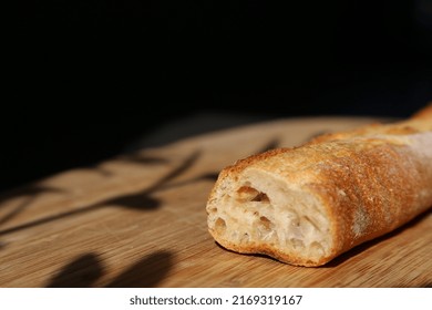 Long Baguette On Wooden Chopping Board With Shadows