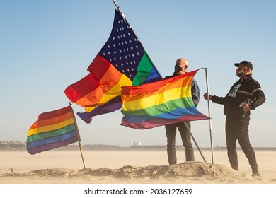 Long Beach, California - March 24, 2021: Two Men Hold Up LGBT Pride Flags In Place Of A Pride-themed Lifeguard Tower That Was Burned Down Two Nights Prior.  