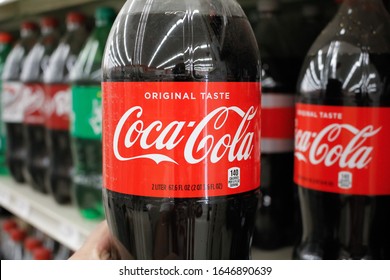 Long Beach, California/United States - 02/12/2020: A hand holds a 2-liter bottle of Coca-Cola soda on display at a local grocery store.