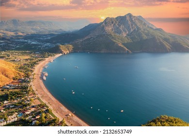 Long beach coast, dark teal sea and bay in Adrasan village Mediterranean coast, great place for holiday. background mountains, forest and sunrise sky. Aerial view with drone. Antalya, TURKEY