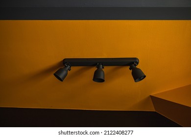 Long Black Sconce With Three Lamps Hanging On Yellow Wall