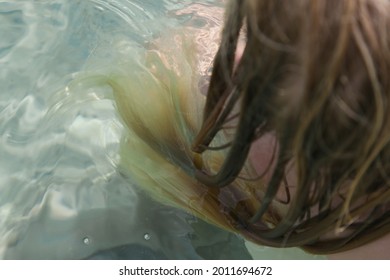 Long Blonde Hair Floating In The Water. Wet Hair Close Up Image. Hair Damage Due To Salty Ocean Water And Sun, Summertime Hair Care Concept.