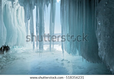 Long  blue icicles in the ice cave at coastal cliffs. Unusual natural phenomena of winter Lake Baikal