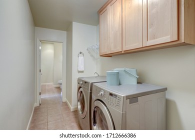 Long Bright Laundry Room Interior With Washer And Dryer And Birch Tree Wood Cabinets.