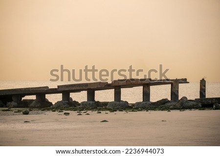 Long broken sea bridge for watching sunrise - sunset and fishing. Broken sea bridge with sea waves during morning time with warm tone. Calm and peaceful beach