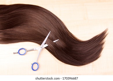 Long Brown Hair And Scissors On Wooden Background