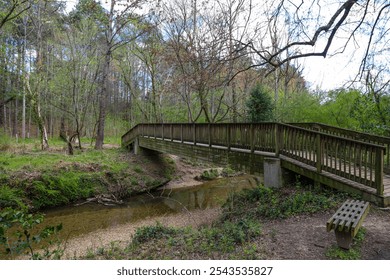 a long brown wooden bridge surrounded by tall thin bare winter trees and lush green trees and plants with blue sky and clouds at Murphey Candler Park in Atlanta Georgia USA - Powered by Shutterstock