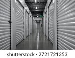 Long corridor inside a modern self storage facility. Empty storage hallway with metal roll up doors. Clean and secure indoor storage units for rent. Symmetrical storage corridor with industrial.