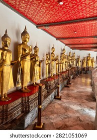 A long corridor lined with rows of golden Buddha statues inside a traditional Buddhist temple.