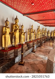 A long corridor lined with rows of golden Buddha statues inside a traditional Buddhist temple.