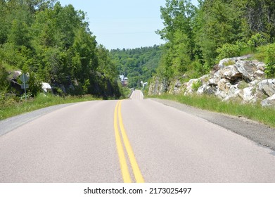 A Long Country Road With Rock Cutouts.