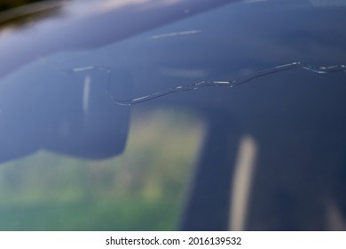 Long crack in the windshield of a car. Caused by hail and stone impact. Insurance claim.