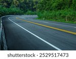 Long curvy forest asphalt road over the hills. Beautiful curved road in the forest. Side view of road 