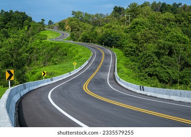 Long curvy forest asphalt road over the hills. Beautiful curved road in the forest. Side view of road.