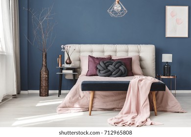 Long Decorative Dark Vase With Branches Next To Bedside Cabinet In Pastel Bedroom With Blue Wall