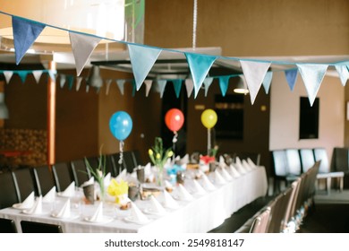 A long dining table decorated for a celebration with colorful balloons, bunting, flowers, and elegant table settings, creating a festive and cheerful indoor atmosphere - Powered by Shutterstock