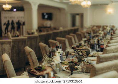 Long dining table elegantly set with food, drinks, and floral decorations for a wedding reception or formal event