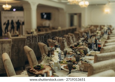 Long dining table elegantly set with food, drinks, and floral decorations for a wedding reception or formal event