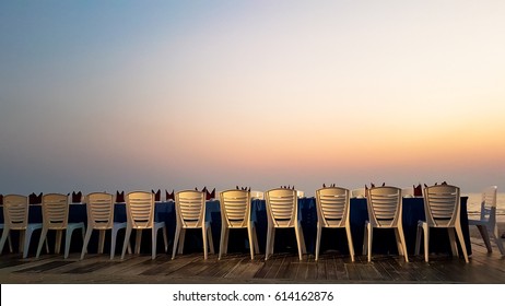 Long Dinner Table And Chair With Red Apron  On The Sand Beach