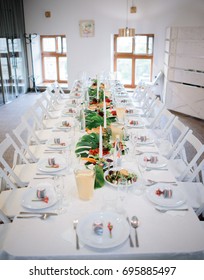 Long dinner table served with plates with salad and greenery