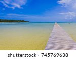 The Long Dock in Cherokee Sound, Marsh Harbour, Abaco, The Bahamas. Old wooden dock stretches out over sea with beautiful blue sky in the background.