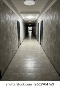 Long empty corridor in a modern building. Perspective view of a hotel or office hallway with doors and ceiling lights.