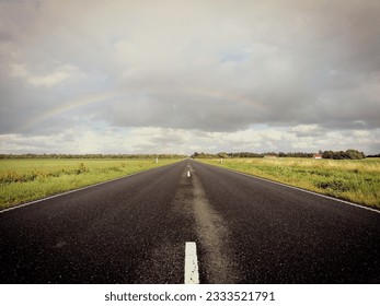 Long empty road with rainbow in the background 