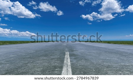 A long, empty runway extends into the distance, meeting the horizon under a vast blue sky dotted with fluffy white clouds.