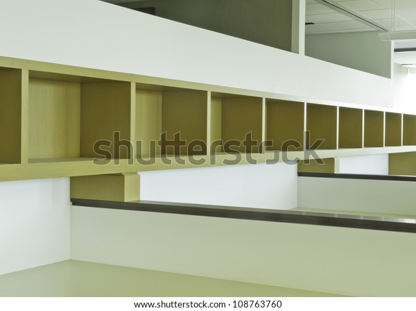 Long empty wooden bookshelf with dividers above\
office cubicles
