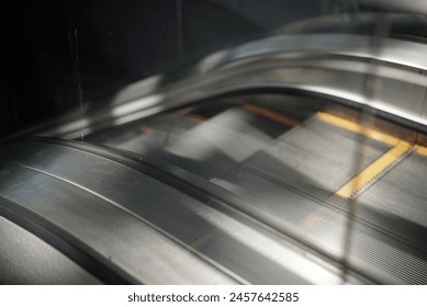 A long escalator ascending towards a ceiling that is not in view. The sides of the escalator are made of metal with a brushed finish. There are no people on the escalator. - Powered by Shutterstock