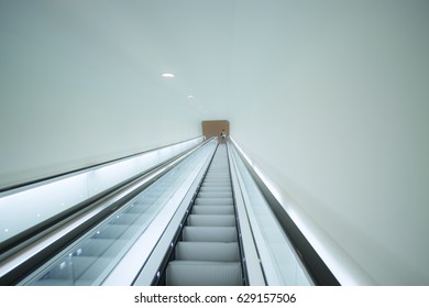 Long Escalator Set In Bright Light With A Nice Line Towards A Vanishing Point In The Middle.