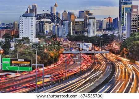Long exposure blurred vehicle motion on multi-lane Warringah freeway going through North Sydney in Sydney, Australia. Headlights during rush hour commute towards Sydney harbour bridge and CBD towers.
